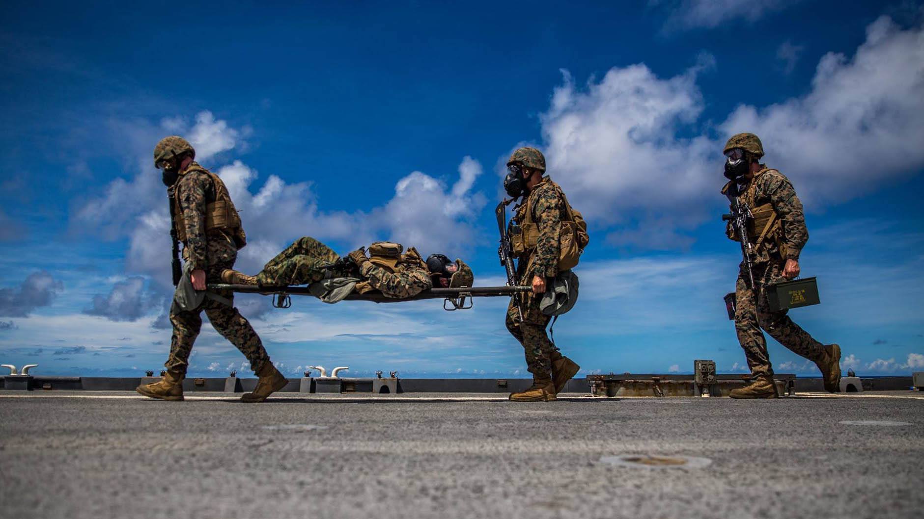 Marines with Combat Logistics Battalion, 11th Marine Expeditionary Unit, run to the finish line of a circuit course while carrying a simulated patient and ammunition cans around the flight deck of USS Comstock April 24. In order to keep themselves physically, mentally, and operationally fit while on deployment, the Marines with CLB-11 have been conducting squad-level competitions that encompass a wide range of operational skill sets, such as physical fitness sessions, weapons handling drills, and casualty combat care drills. (U.S. Marine Corps photo by Cpl. Devan K. Gowans)