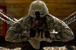 Staff Sgt. Marcus Thomas holds onto a chain creating a human bridge on Oct. 22, 2010, at Camp Bullis, Texas. Security forces Airmen use teamwork to complete various obstacles at the Leadership Reaction Course during the Combat Leadership Course. (U.S Photo/Staff Sgt. Jonathan Snyder)