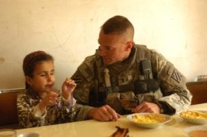 Noor, a young girl receiving eye surgery in the U.S., entertains 1st Lt. Michael Kendrick while he eats breakfast at her family's house in al-Buaytha, Iraq, May 25. Noor suffers from sclerocornea, a condition which has left her blind since birth. With help from Kendrick and other Soldiers of 1-30th Inf. Regt., she is traveling to the U.S. for surgery that may restore her vision. Photo by Sgt. David Turner<br /> see http://www.army.mil/-news/2008/05/27/9433-iraqi-girl-travels-to-us-in-effort-to-repair-vision/