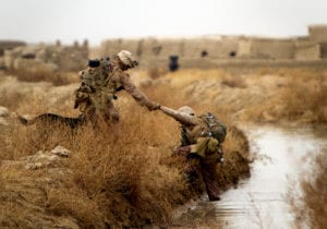 U.S. Marine Lance Cpl. Brandon Mann, a dog handler with Alpha Company, 1st Light Armored Reconnaissance Battalion, and native of Arlington, Texas, helps Sgt. Guillermo Floresmartines, an assistant squad leader with Alpha Co., 1st LAR, and 25-year-old native of Menifee, Calif., out of a canal during a patrol here, Feb. 16. Marines and sailors with 1st LAR and India Co., 3rd Battalion, 3rd Marine Regiment, conducted clearing and disrupting operations in and around the villages of Sre Kala and Paygel during Operation Highland Thunder. Marines with 1st LAR led the operation on foot, sweeping for enemy weapons and drug caches through 324 square kilometers of rough, previously unoccupied desert and marshland terrain. Mobile units with1st LAR set up blocking positions and vehicle check points while India Co., 3/3 conducted helicopter inserts to disrupt insurgent freedom of movement.