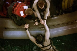 SOUTH CHINA SEA (Nov. 15, 2015) A U.S. Sailor with the Essex Amphibious Ready Group is pulled out of the water during a transition of safety divers during a swim call aboard the USS Essex (LHD 2). The Marines and Sailors of the 15th Marine Expeditionary Unit and Essex ARG jumped 30-feet into the water and swam to their respective check point. The 15th MEU is currently deployed in the Indo-Asia-Pacific region to promote regional stability and security in the U.S. 7th Fleet area of operations. (U.S. Marine Corps photo by Cpl. Elize McKelvey/Released)