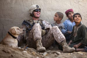 U.S. Marine Lance Cpl. Isaiah Schult, a 20-year-old Indianapolis native and improvised explosive device dog handler with Jump Platoon, Headquarters and Service Company, 3rd Battalion, 3rd Marine Regiment, jokes with Afghan children and a Afghan National Police member outside a local residence here, Nov. 22. Following their recent assumption of security responsibility in Garmsir, the leadership of â€œAmericaâ€™s Battalionâ€ joined District Governor Mohammad Fahim to visit and interact with citizens throughout the district, Nov. 22 to 24. During the visits, Fahim and the Marines discussed issues like tribal unity, education, insurgent activity and the continued development of the Afghan National Army and Police. â€œWeâ€™re bringing governance to ungoverned places,â€ said Lt. Col. Matthew Palma, 3/3 commanding officer. â€œNow, itâ€™s up to the Afghan people to work together with their government to make the changes required to become free.â€